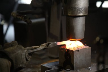 Isıtılmış malzemeleri çekiçle şekillendiren bir zanaatkar..