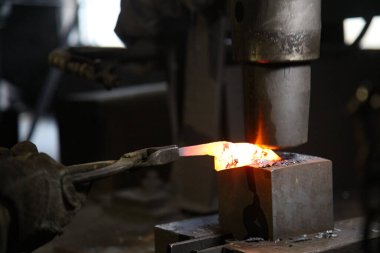 Isıtılmış malzemeleri çekiçle şekillendiren bir zanaatkar..