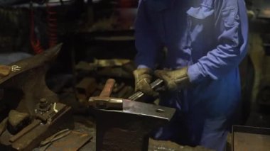 Isıtılmış malzemeleri çekiçle şekillendiren bir zanaatkar..