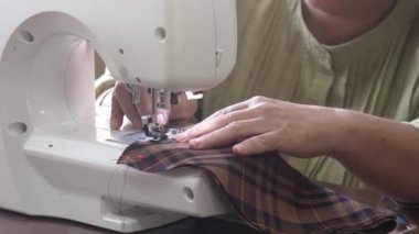 Dikiş makinesi kullanan bir kadın.