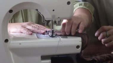 Dikiş makinesi kullanan bir kadın.