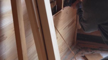 Bir adam vidaları elektrikli tornavidayla duvardan söküyor.