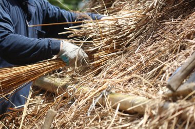 Bir zanaatkar sazdan çatıyı tamir ediyor.