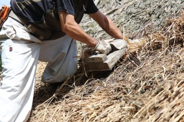 Bir zanaatkar sazdan çatıyı tamir ediyor.