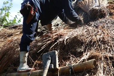 Bir zanaatkar sazdan çatıyı tamir ediyor.
