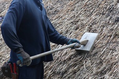 Bir zanaatkar sazdan çatıyı tamir ediyor.