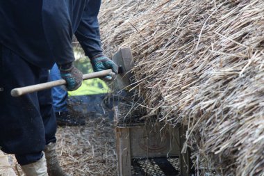 Bir zanaatkar sazdan çatıyı tamir ediyor.