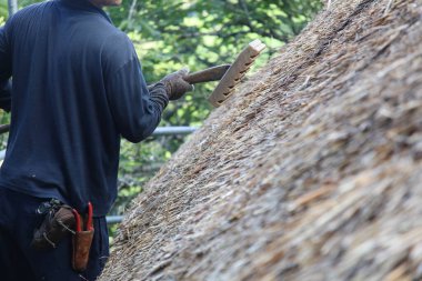 Bir zanaatkar sazdan çatıyı tamir ediyor.