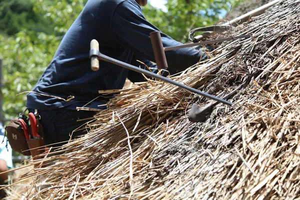 Bir zanaatkar sazdan çatıyı tamir ediyor.