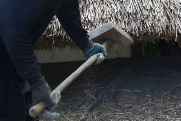 Bir zanaatkar sazdan çatıyı tamir ediyor.