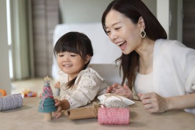 Ebeveynler ve çocuklar küçük bir Noel ağacı süslüyorlar.