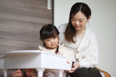 Küçük bir piyano çalan ebeveyn ve çocuk.