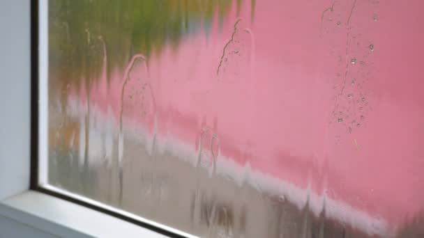 Regen beukt op vensterglas, regenbui, regenseizoen, verdriet, ontspanning. Straat en dak van het huis buiten het raam. — Stockvideo