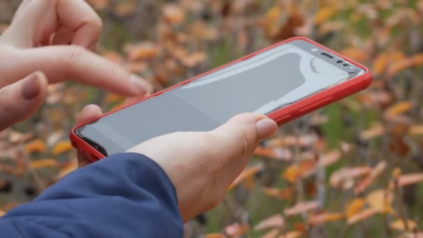 Broken red phone screen. Close up of womans hand touching red mobile phone with blurred yellow green background, by sending SMS messages. — Stock Video