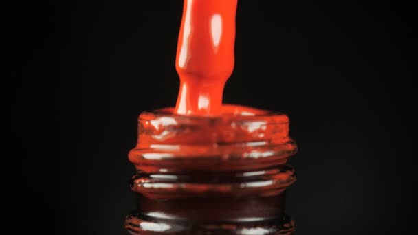 Rode gel nagellak met een open fles en een druppel druppelend in een pot met een borstel in de schoonheidssalon. Zwarte achtergrond. Close-up. — Stockvideo