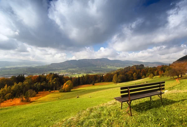 Panorâmica ensolarada outono vista alpina com banco — Fotografia de Stock