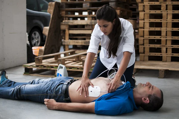 Rescuer applying defibrillator electrodes — Stock Photo, Image