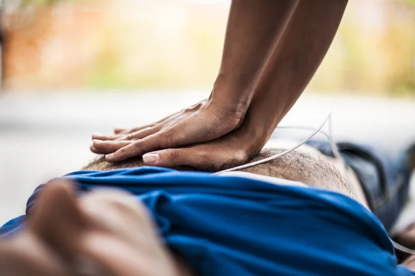 Girl assisting an unconscious man with defibrillator and CPR — Stock Photo, Image