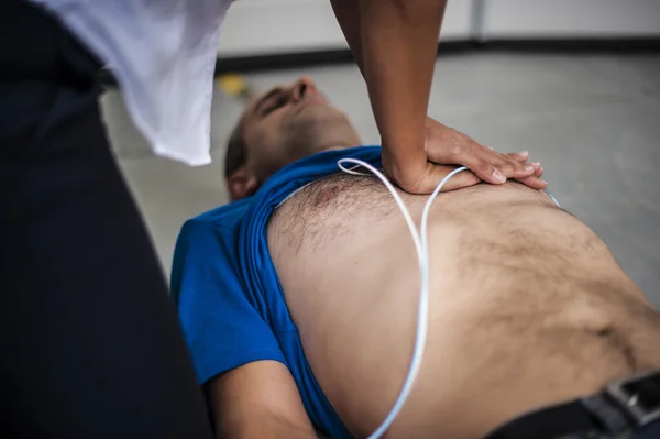 Girl assisting an unconscious man with defibrillator and CPR — Stock Photo, Image