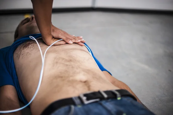 Girl assisting an unconscious man with defibrillator and CPR — Stock Photo, Image