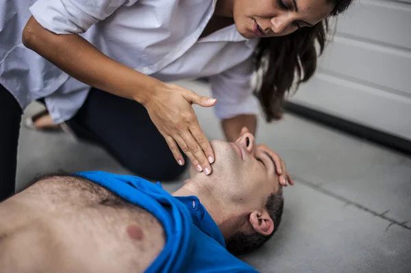 Girl assisting an unconscious man with defibrillator and CPR — Stock Photo, Image