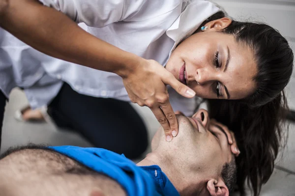 Girl assisting an unconscious man with defibrillator and CPR — Stock Photo, Image