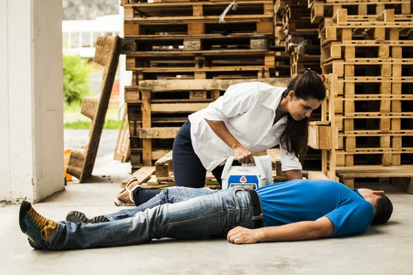 Mädchen hilft bewusstlosem Mann mit Defibrillator — Stockfoto