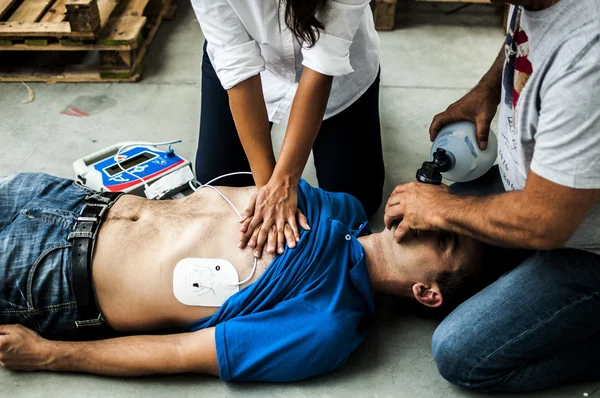 Girl assisting an unconscious guy with CPR — Stock Photo, Image