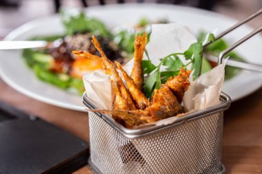 Ahşap bir masada kızartılmış kırmızı kefal balığı sepeti. Alan derinliği