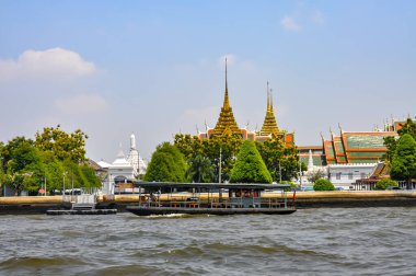 Chao Phraya River panorama in Bangkok, Thailand. Traditional boats and temples against a city skyline. Asian tourism and water transport.
