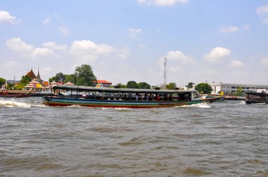Chao Phraya River panorama in Bangkok, Thailand. Traditional boats and temples against a city skyline. Asian tourism and water transport.