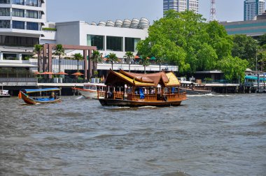 Chao Phraya River panorama in Bangkok, Thailand. Traditional boats and temples against a city skyline. Asian tourism and water transport.
