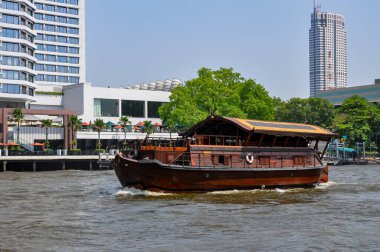 Chao Phraya River panorama in Bangkok, Thailand. Traditional boats and temples against a city skyline. Asian tourism and water transport.