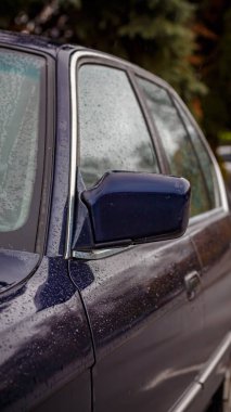 Boş bir sonbahar otoparkında klasik bir sedan. Lacivert yağmurla kaplı bir araba. Islak asfalt üzerinde duruyor.