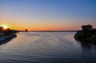 Dnipro City, Ukrayna 'da Dnipro River Embankment üzerine panoramik Günbatımı: Binaların, İnsanların ve Trafiğin Silüetleri Altında Şehir