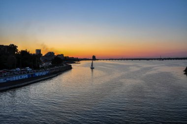 Dnipro City, Ukrayna 'da Dnipro River Embankment üzerine panoramik Günbatımı: Binaların, İnsanların ve Trafiğin Silüetleri Altında Şehir