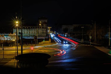 Yoğun bir kavşakta arabalardan gelen ışık izleriyle dinamik gece şehirleri: kentsel yaşam ve hareket kavramı.