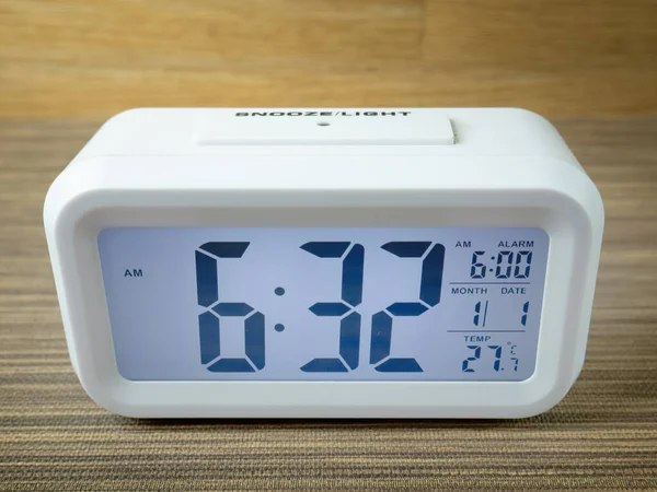 white alarm clock digital numbers on wood table.