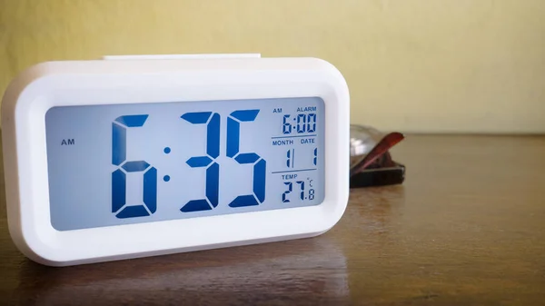 white alarm clock digital numbers on wood table.