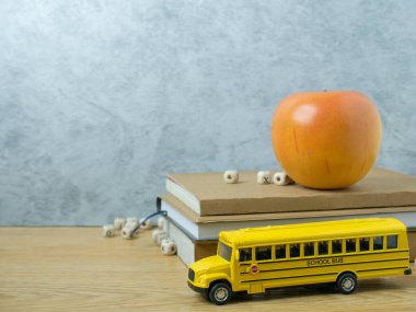 Okul otobüsü oyuncağı ve elma ahşap masada okula dönmek ya da eğitim danışmanı olmak için.