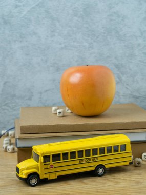 Okul otobüsü oyuncağı ve elma ahşap masada okula dönmek ya da eğitim danışmanı olmak için.