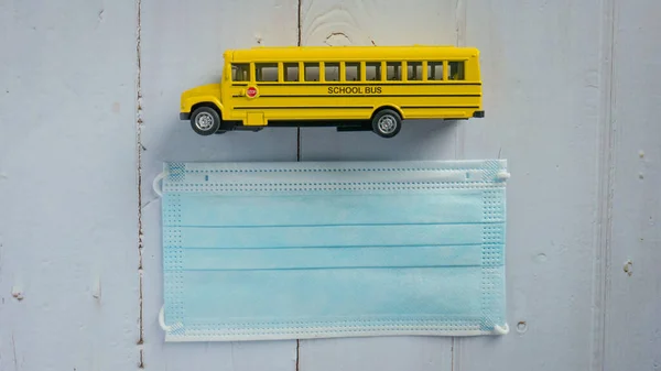 The school bus and mask on wood table for education  or medical  concept