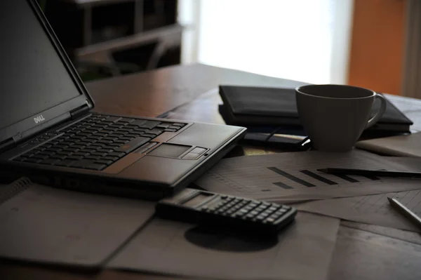 Arbeitsplatz mit offenem Laptop mit schwarzem Bildschirm und Geschäftsdokumenten — Stockfoto