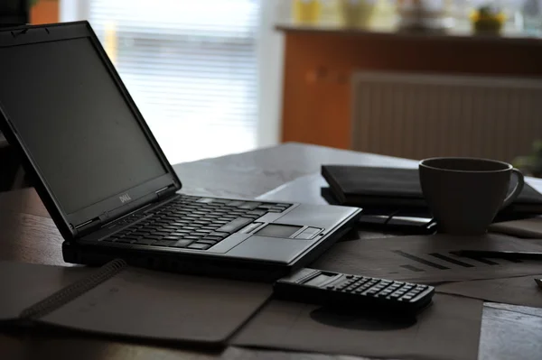 Arbeitsplatz mit offenem Laptop mit schwarzem Bildschirm und Geschäftsdokumenten — Stockfoto