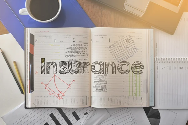 Notizbuch mit Text innerhalb der Versicherung auf dem Tisch mit Kaffee und ein paar Papieren herum — Stockfoto