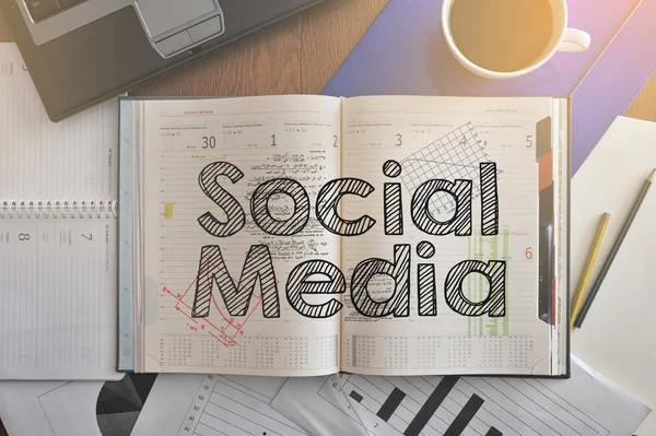 Caderno com texto dentro das mídias sociais na mesa com café e alguns papéis — Fotografia de Stock