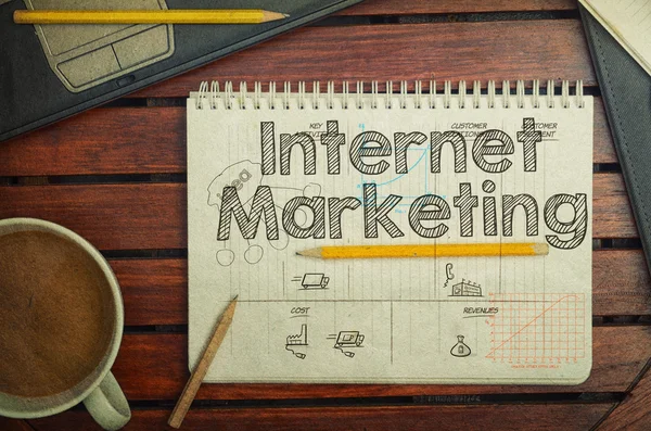 Notitieboekje met tekst in Internet Marketing op tafel met koffie — Stockfoto