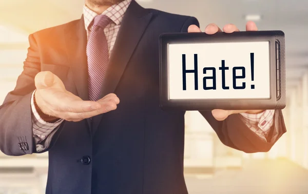 Businessman showing business concept on tablet standing in office: Hate — Stock Photo, Image