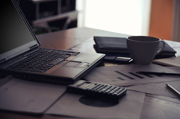 Arbeitsplatz mit offenem Laptop mit schwarzem Bildschirm und Geschäftsdokumenten — Stockfoto