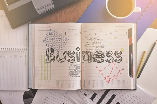 Notebook with text inside Business on table with coffee and some diagrams — Stock Photo, Image